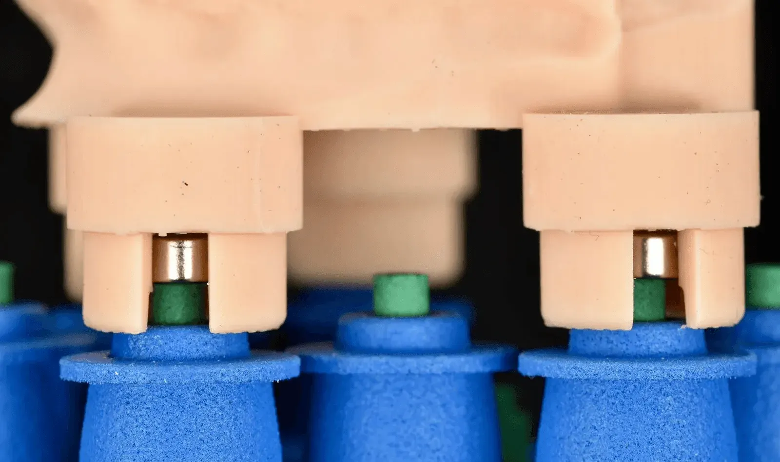 Close-up of magnets set in the seats of a printed model base, resting on the placement tools