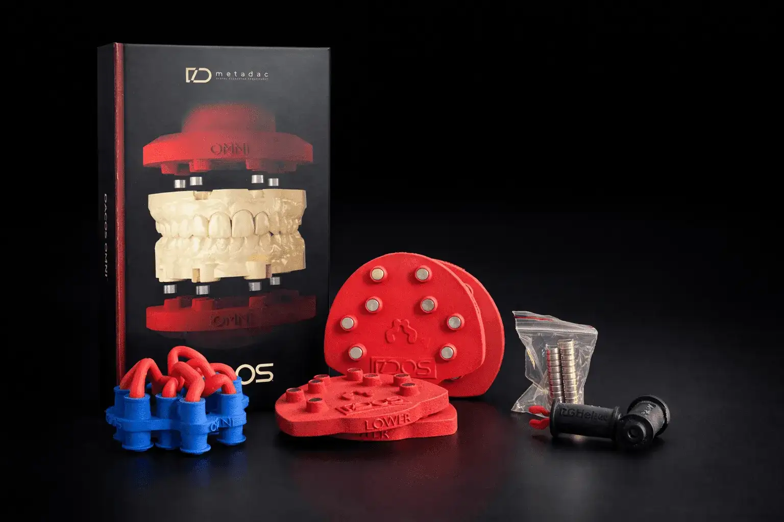 The DACOS Omni kit in front of its box: red upper and lower plates with their magnets, a bag of spare magnets and the magnet placement tools