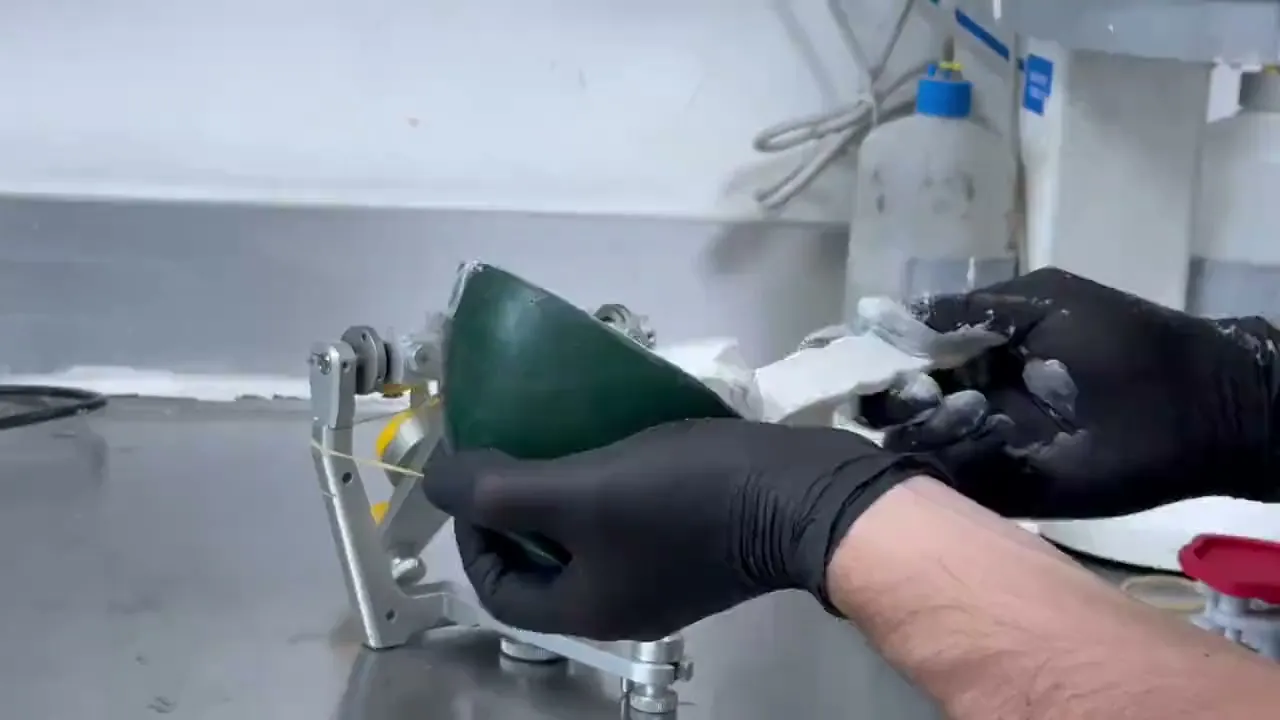 Mains gantées fixant au plâtre les plaques Flex sur les plaques de montage de l’articulateur, le calibrateur entre les deux