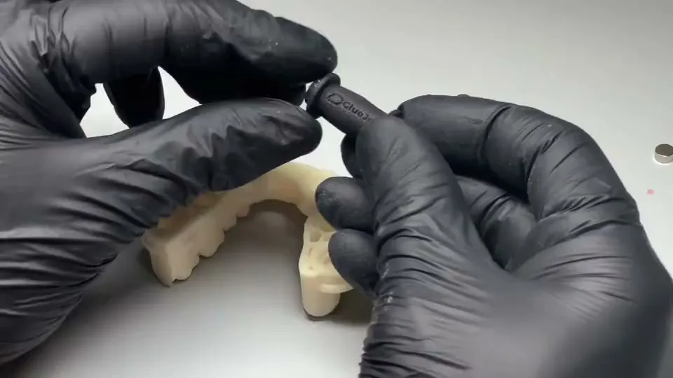 Mains gantées insérant un aimant dans un modèle imprimé avec l’Omni GlueJet