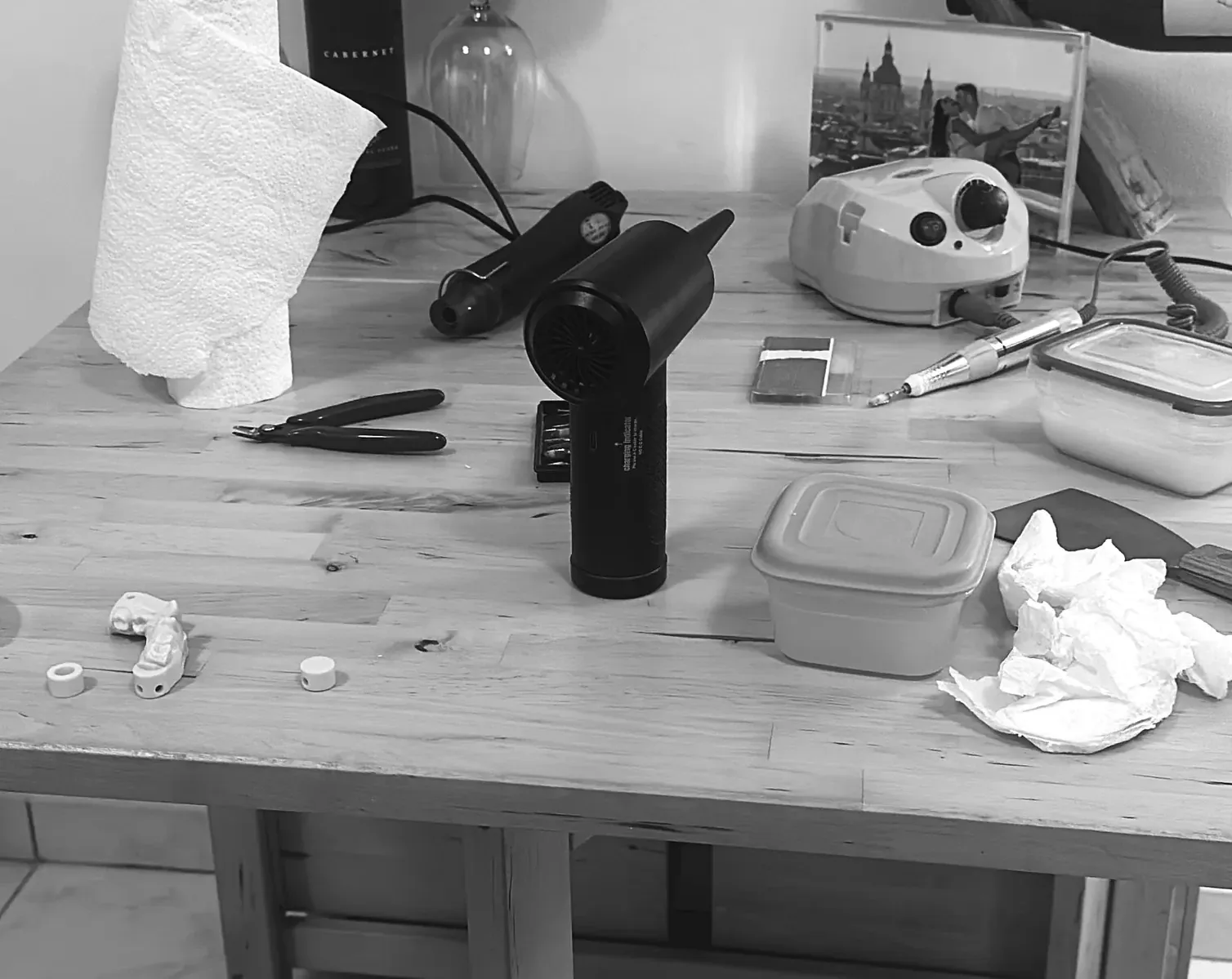 Photo en noir et blanc d’un poste de travail à la maison avec du matériel de CAO, des outils et des pièces imprimées